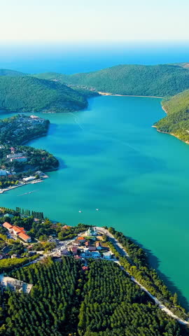Vertical video. Abrau-Diurso, Krasnodar Krai, Russia. Lake Abrau. Embankment and village. Summer. Fields with vineyards on the hills. Aerial View. Rich colors