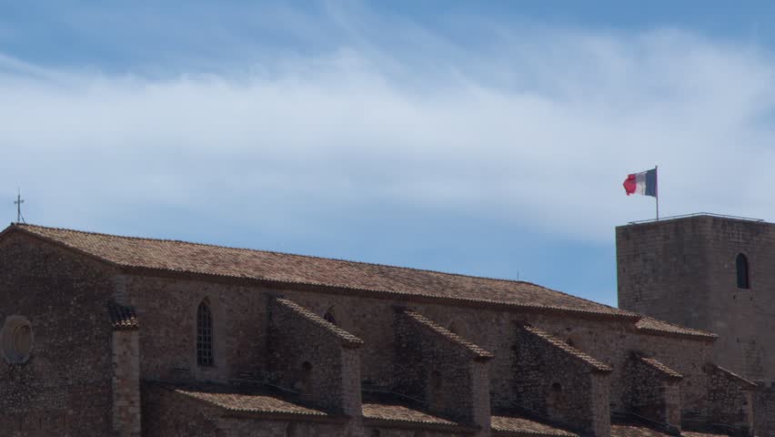 Static wide shot of a medieval stone church and bell tower under blue skies.