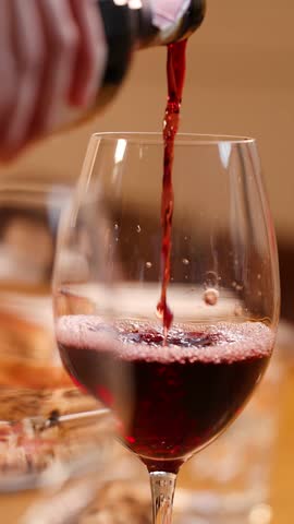Close-up shot of red wine pouring into a glass during an elegant restaurant meal.