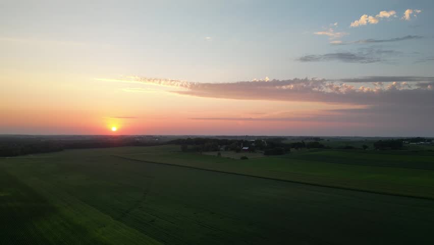 Flying forward and across towards a farm in the middle of an epic sunset over the Iowa corn fields like the ending of a movie. 
