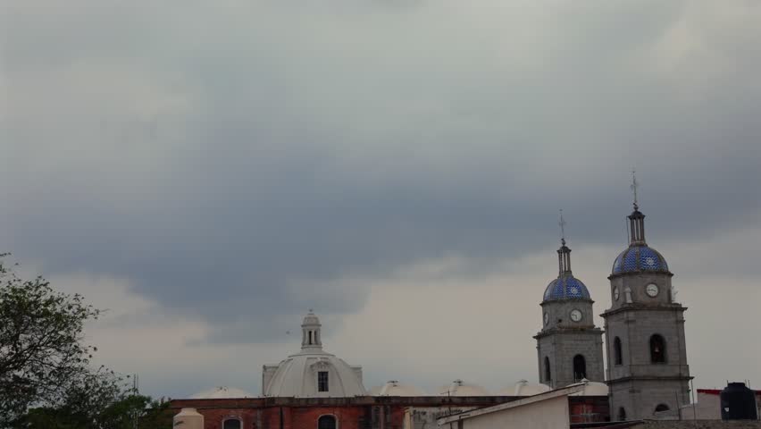 Timelapse of storm clouds gathering above San Juan Bautista Temple bell towers in Tuxpan Jalisco Mexico before rainfall with an overcast sky over the historic city center during daytime