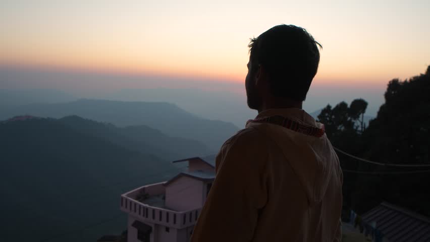 A man stands looking at a scenic golden sunset over the mountain ranges in Chakrata, Dehradun, Uttarakhand.