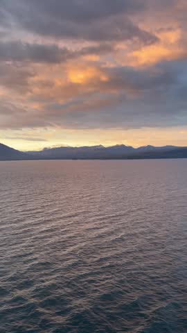 Golden sunset over ocean with mountains and cloudy sky in Alaska

Beautiful golden hour sunset over calm ocean water with mountains and dramatic orange clouds in Alaska, scenic travel background
