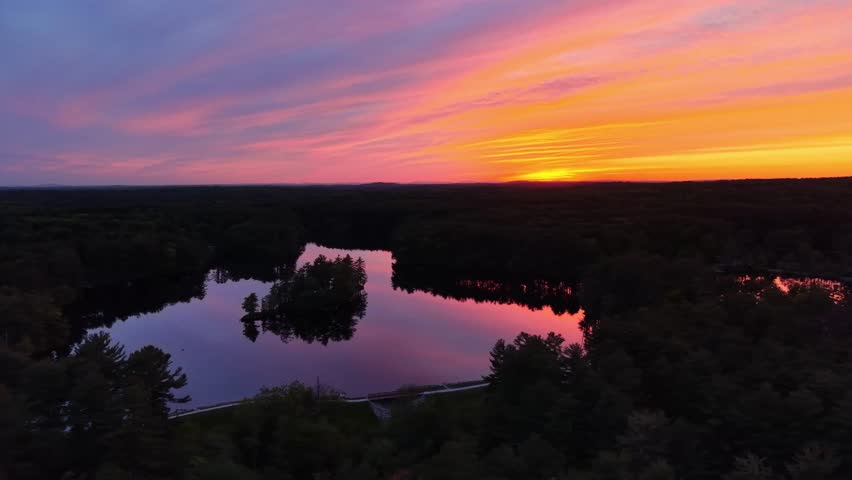 Stunning aerial view of pink and orange sunset reflecting on a tranquil lake at Harold Parker State Forest, Andover, Massachusetts