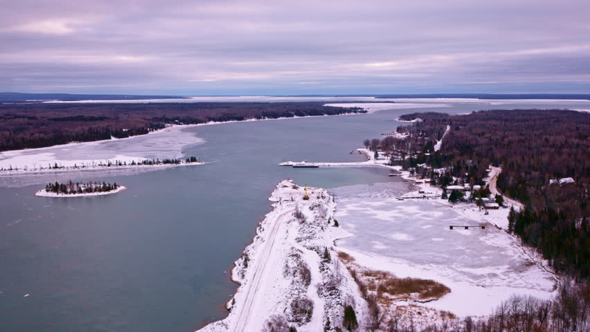 Drone shot of a serene winter landscape leading to the partially frozen waters of Lake Superior Bay.