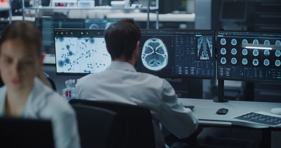 Male Scientist Examines Brain MRI Scans Across Multiple Monitors in Medical Research Laboratory, Applying Ai Computer Technology for Neurology Diagnosis, Drug Development and Disease Treatment.