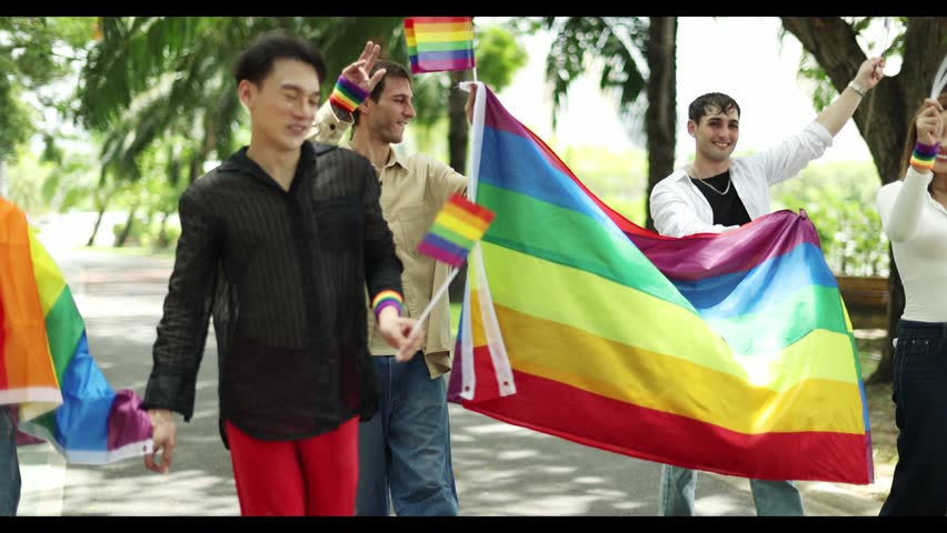 Gathering gay men transgender women and lesbians carrying rainbow flags pride celebrated joy LGBTQ community and their gender identities marching parade demand equal rights and social acceptance LGBTQ community.