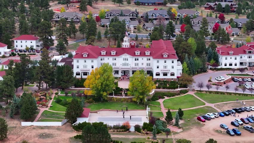 Aerial view of historic Stanley Hotel in Estes Park, Colorado town with fall foliage colors and surrounding cabins and mountain landscapes during the autumn season - 4K Drone