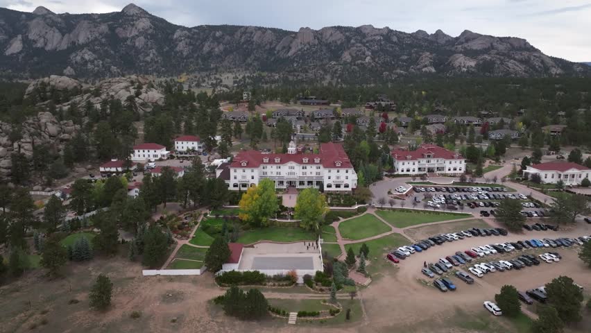 Panoramic aerial view of the historic Stanley Hotel in Estes Park, Colorado town with fall foliage colors and surrounding cabins and mountain landscapes during the autumn season - 4K Drone