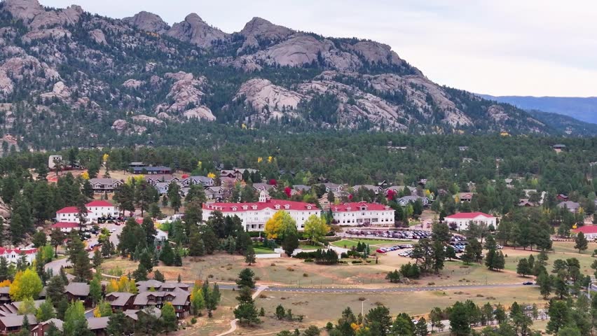 Panoramic aerial view of the historic Stanley Hotel in Estes Park, Colorado town with fall foliage colors and surrounding mountain landscapes during the autumn season - 4K Drone