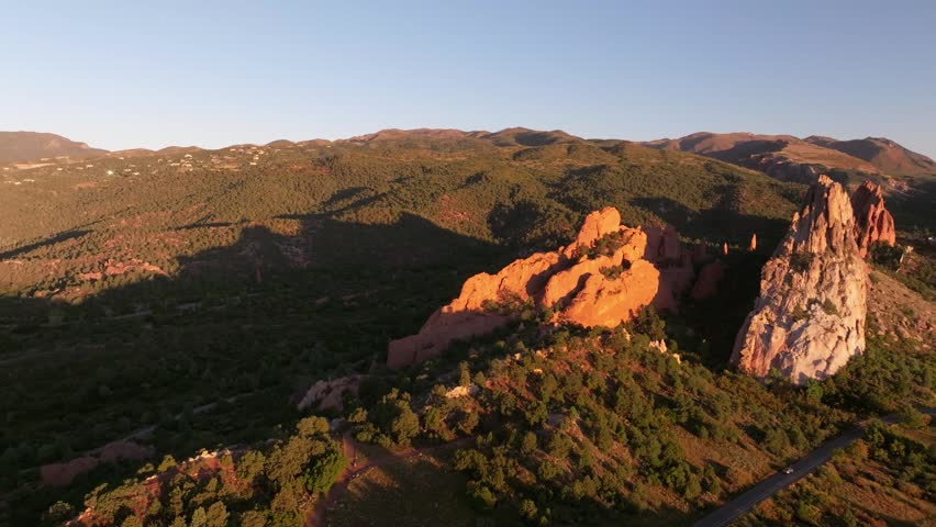 Panoramic aerial view of Garden of the Gods state park rock formation landscapes with sunrise alpenglow light during autumn season in Colorado Springs, Colorado with mountains in background - 4K Drone