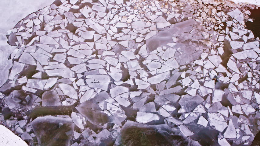 Overhead view of a mostly frozen Great Lake featuring diverse ice shapes and tranquil winter scenery.
