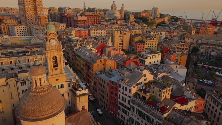 Aerial view over Genoa historic center with narrow streets, churches, and harbor cranes