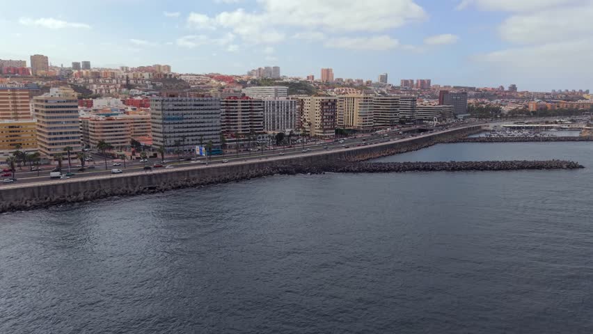 Aerial view of the seafront promenade in Las Palmas, Gran Canaria. City buildings and busy coastal road next to the deep blue Atlantic Ocean