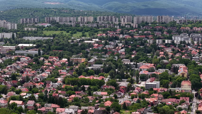 An expansive aerial view of a residential district in Budapest, Hungary, showcasing urban housing nestled within a lush, green landscape.