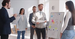 Business team meeting during corporate training. Leader presents strategy at board while colleagues discuss notes and align planning in modern office. Strong leadership and teamwork concept. - Powered by Shutterstock - Get 15% off with code: PIKWIZARD15