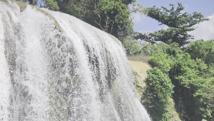 Beautiful tropical waterfall flowing through lush green forest with crystal clear water and a peaceful natural atmosphere. Scenic waterfall landscape in Indonesia, perfect for travel, nature, relaxation, and environmental concepts.