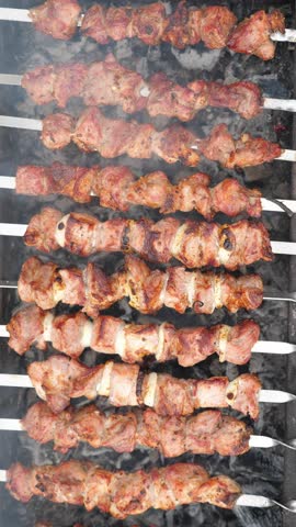 Grilling pork kebab on skewers at bbq, cooking process. Vertical footage