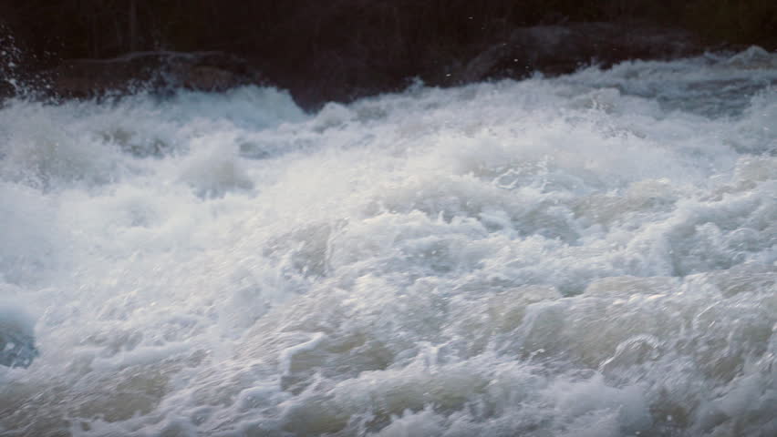 Churning rapids rush through Sauble Falls in Ontario during the spring runoff. The slow motion reveals individual water droplets hanging in the air above the turbulent, foaming river.