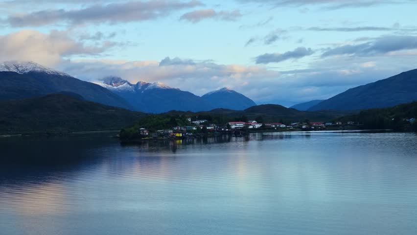 Early morning view of Puerto Edén, Chile, as first light illuminates cold Patagonian fjord waters and the Andes Mountains in a serene coastal landscape