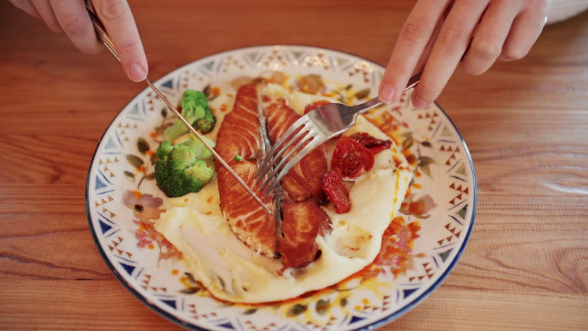 Close up of grilled salmon fillet served with creamy mashed potatoes, roasted cherry tomatoes, and broccoli