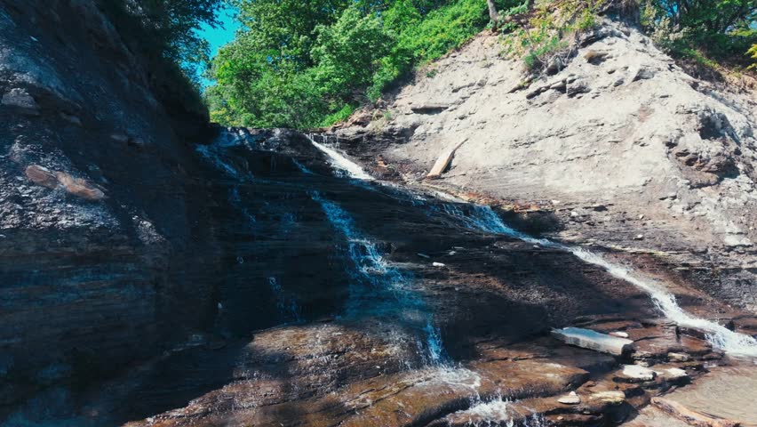 A flowing and trickling waterfall over a stone cliffside.
