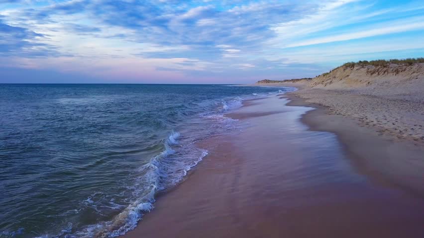 Sandy shoreline and calm blue sea beside coastal dunes