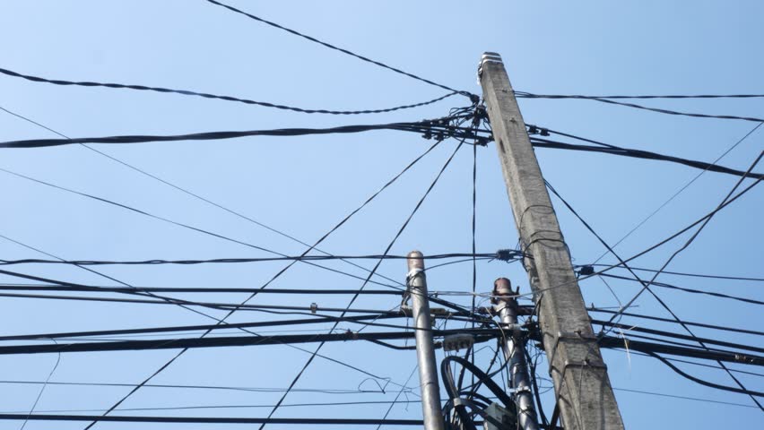 Utility Pole and Overhead Power Lines Viewed From Below Against Clear Blue Sky
