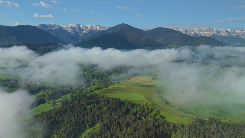 Snow capped Pyrenees mountains above misty valley and forests in Catalonia
