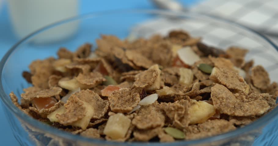 Fresh milk pouring into crispy cereal flakes in white bowl in ultra slow motion