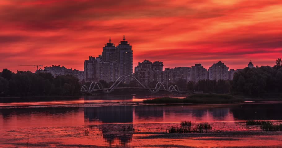 Beautiful colourful sunset over Obolon Embankment in Kyiv, Ukraine, calm reflections on the water, and a glowing city skyline in warm evening light.