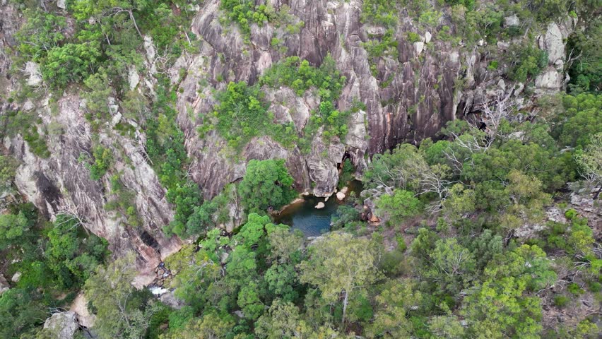 A drone footage of a river between rocky cliffs with vegetations at Mount Barney National Park in Australia