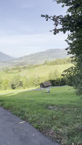 Beautiful rural landscape in Schwyz, Switzerland, with green hills, a traditional Swiss barn, mountain scenery and peaceful countryside under soft natural light.