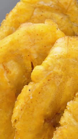 Fried platanos on plate. Sliced and cooked tostones. Rotating. Vertical footage
