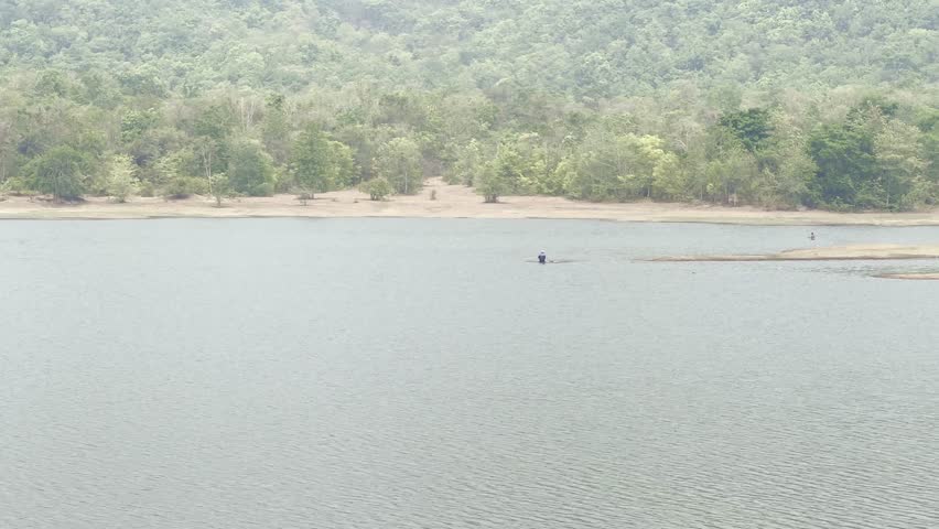 A person casting a fishing net in a reservoir.