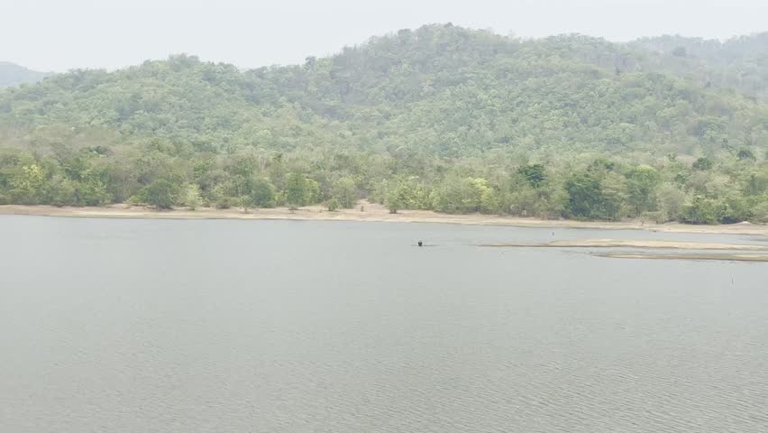 A person casting a fishing net in a reservoir.