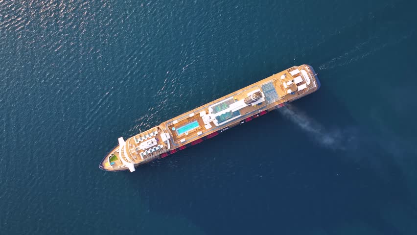Cruise ship moves through the Mediterranean Sea. Passengers relax on deck. The journey highlights maritime tourism in summer. Views of ocean and coastline visible.