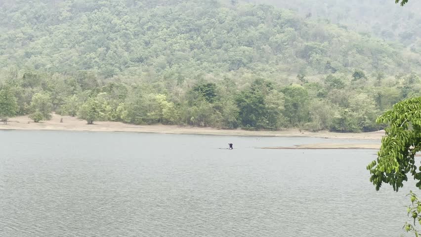A person casting a fishing net in a reservoir.