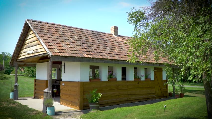 A charming cottage with a porch, with tree branches hanging into the foreground.