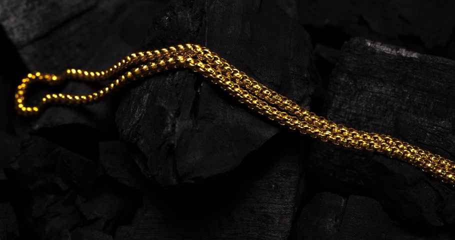 Closeup shot of gold necklaces on charcoal with rotating
