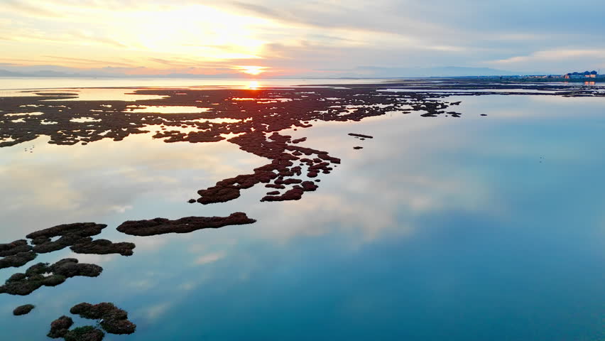 Salt marsh islands and calm lagoon water during sunset. Aerial view of coastal wetland with evening sky reflection