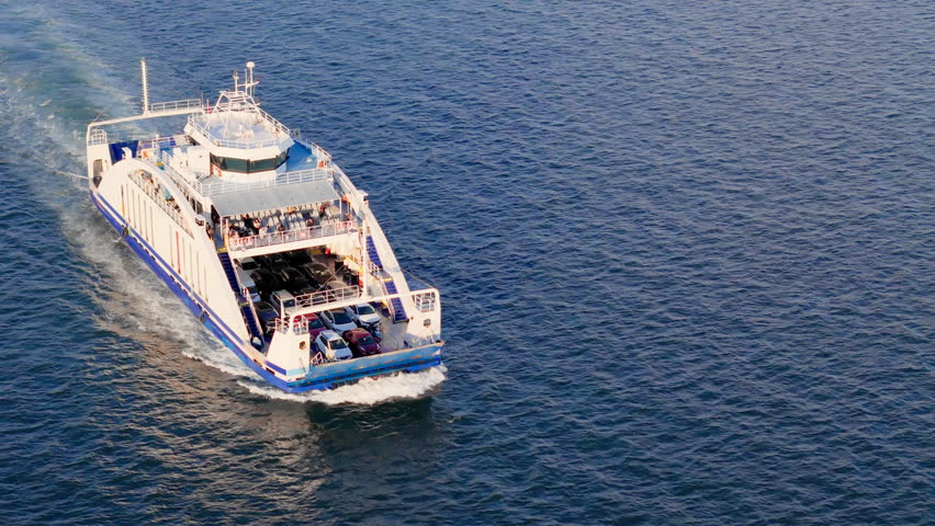 Car ferry transporting vehicles across bay water. Public ferry service connecting road traffic over water