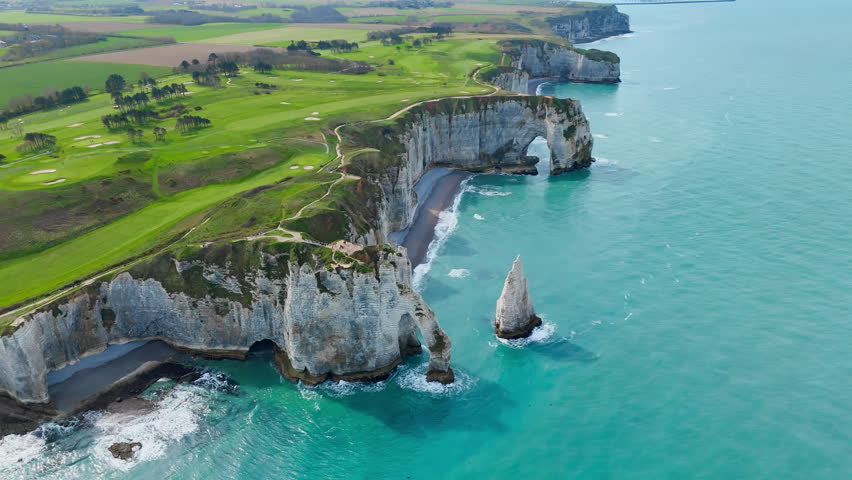Etretat coast in Normandy, France, with limestone cliff formations and English Channel sea. Aerial footage of iconic French coastline