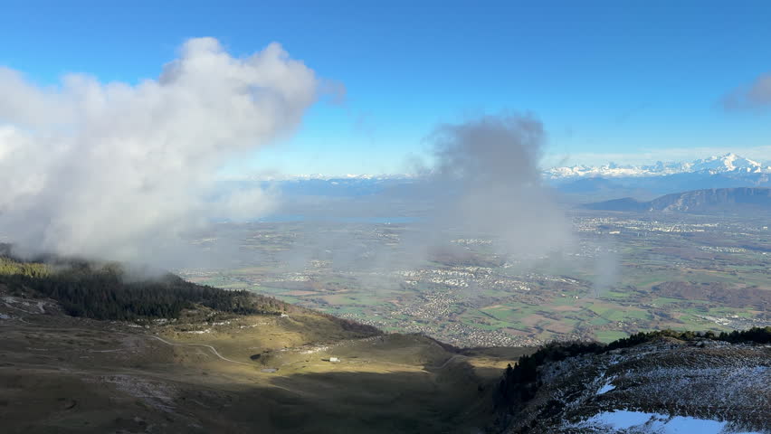 Pan right shot of Jura region seen from mountaintop amidst clouds on sunny day