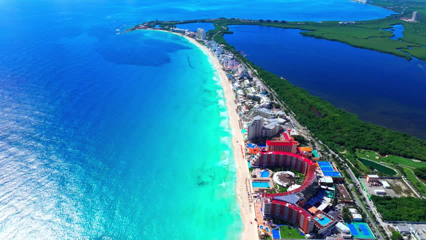 Aerial view of the turquoise Caribbean shoreline and resorts of the Cancun Hotel Zone, Quintana Roo, Mexico, white sand curving beside the lagoon.