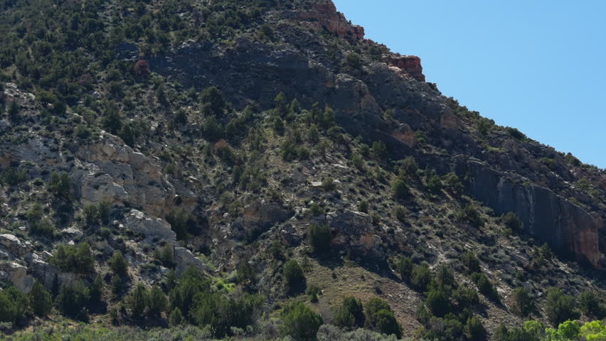 Steep rocky canyon slope above the Yampa River in Colorado, establishing pan right