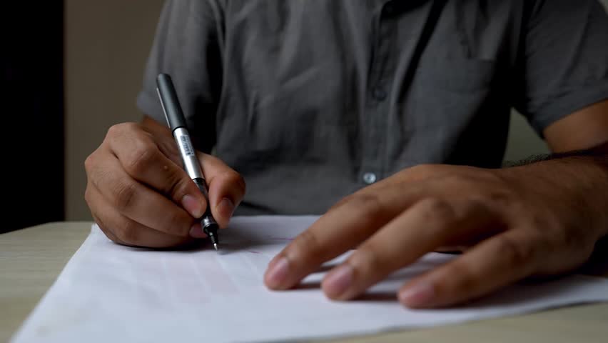 Close-up of Hands Writing with Pen on Paper