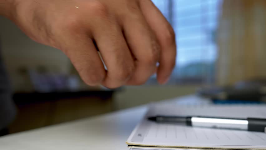 Close-Up of Hand Writing with Pen on Paper