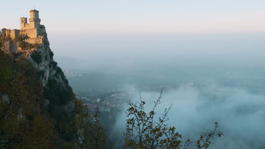 Guaita Tower in San Marino, perched on Monte Titano rock at foggy sunset. Medieval fortress in Republic of San Marino. Travel and touristic landmark in Europe