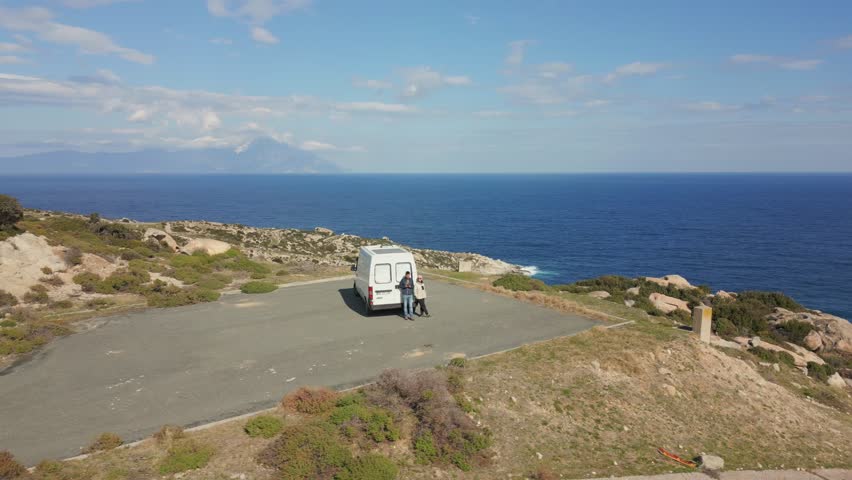 Couple with Camper van with solar panels on the roof parked on Kriaritsi project area drone aerial top view with abandoned roads in the cliffs of south of Greece